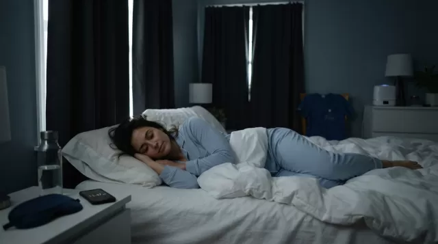 Nurse sleeping in darkened bedroom during day with blackout curtains after night shift