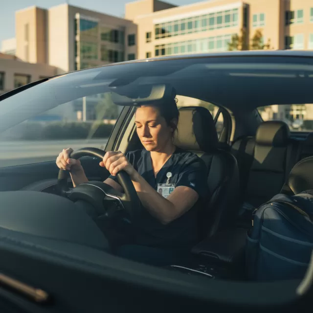 Physical therapist sitting alone in car after emotional patient discharge in hospital parking lot
